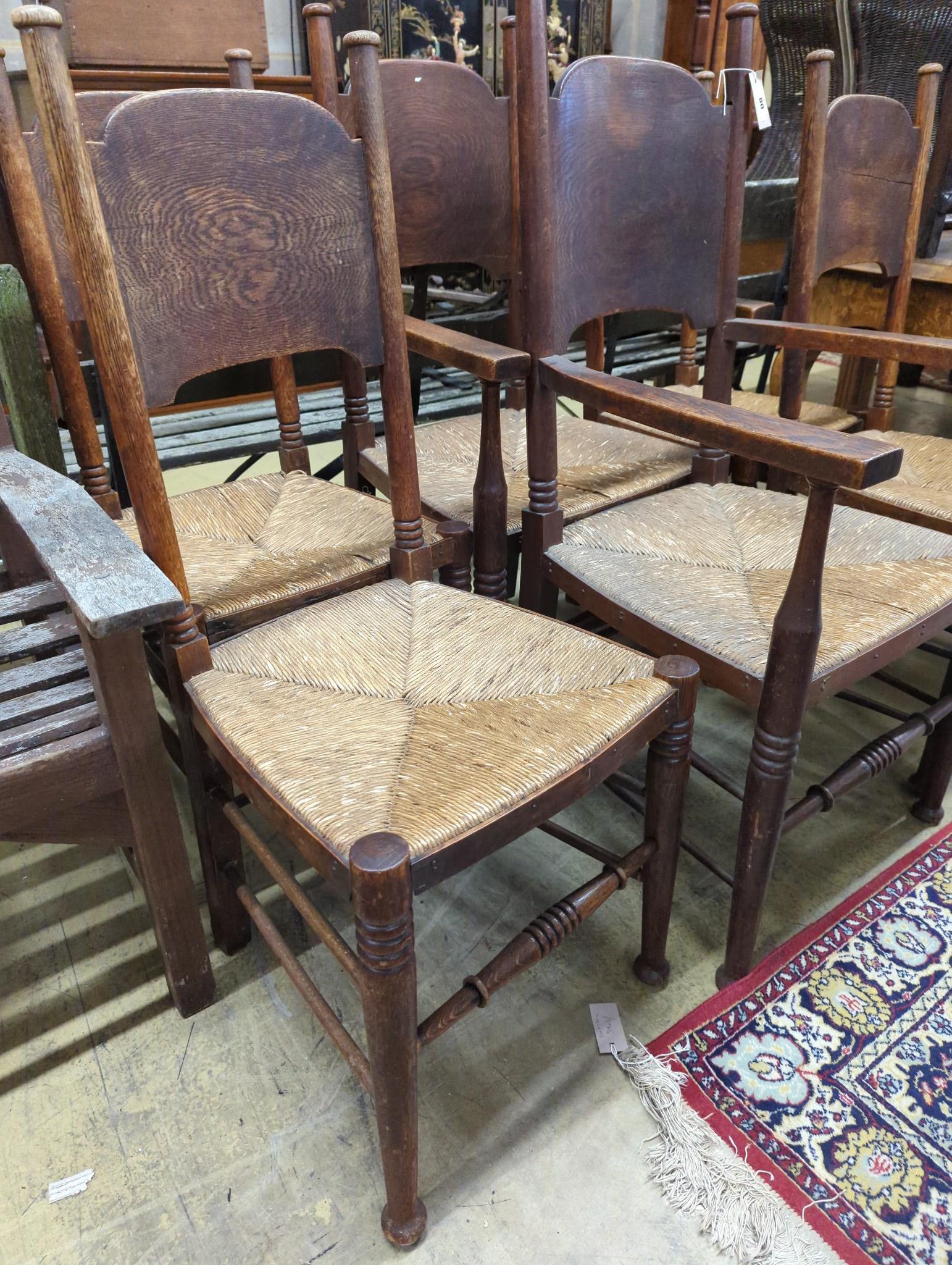 A set of six Arts & Crafts oak chairs, including a pair of carvers, in the Glasgow School manner by William Birch, High Wycombe, with shaped panels backs, ring turned frames and rush seats, carvers W.58cm D.54cm H.109cm